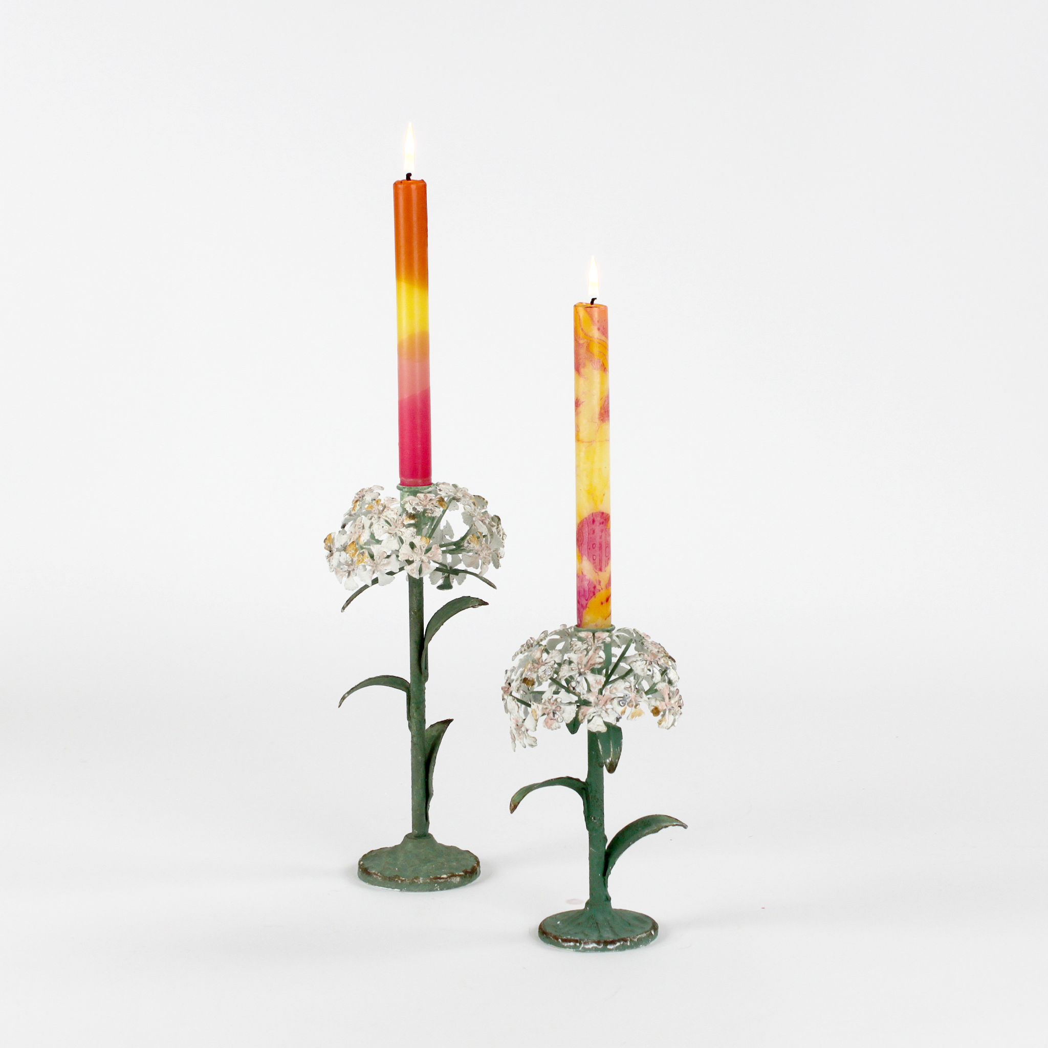 Two decorative metal hydrangea flower sculptures with colorful candles on a white background