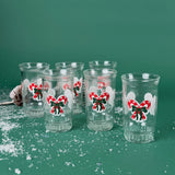 Set of six clear holiday tumblers with red candy cane bow designs on a snowy green background