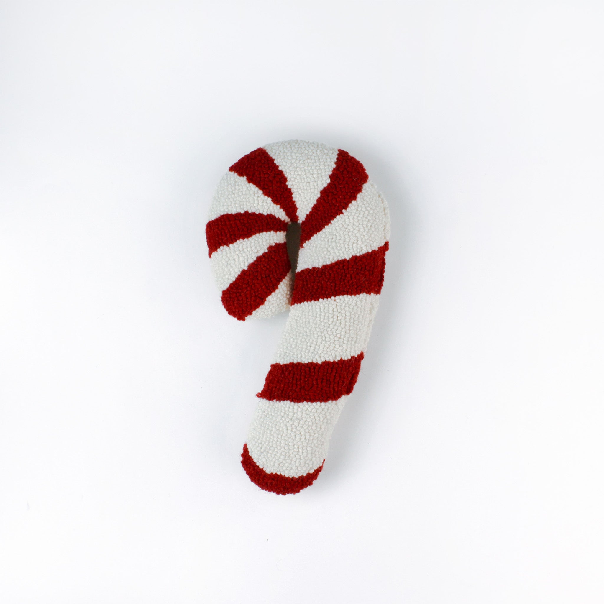 Candy cane–shaped decorative pillow with red and white stripes, made from a textured hooked fabric and displayed against a white background.