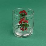Clear holiday drinking glass with red candy cane and green ribbon design on a green background