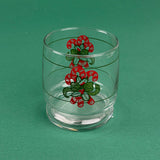 Clear holiday drinking glass with red candy cane and green ribbon design on a green background