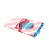 diagonally striped pink christmas tea towel with a large blue ornament motif at the bottom and blue pom pom trim against a white background. 