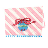 diagonally striped pink christmas tea towel with a large blue ornament motif at the bottom and blue pom pom trim against a white background. 