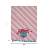 diagonally striped pink christmas tea towel with a large blue ornament motif at the bottom and blue pom pom trim against a white background and dimensions marked 24" x 18.5"