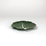 a ceramic green cabbage leaf plate on a white background.