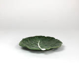 a ceramic green cabbage leaf plate on a white background.