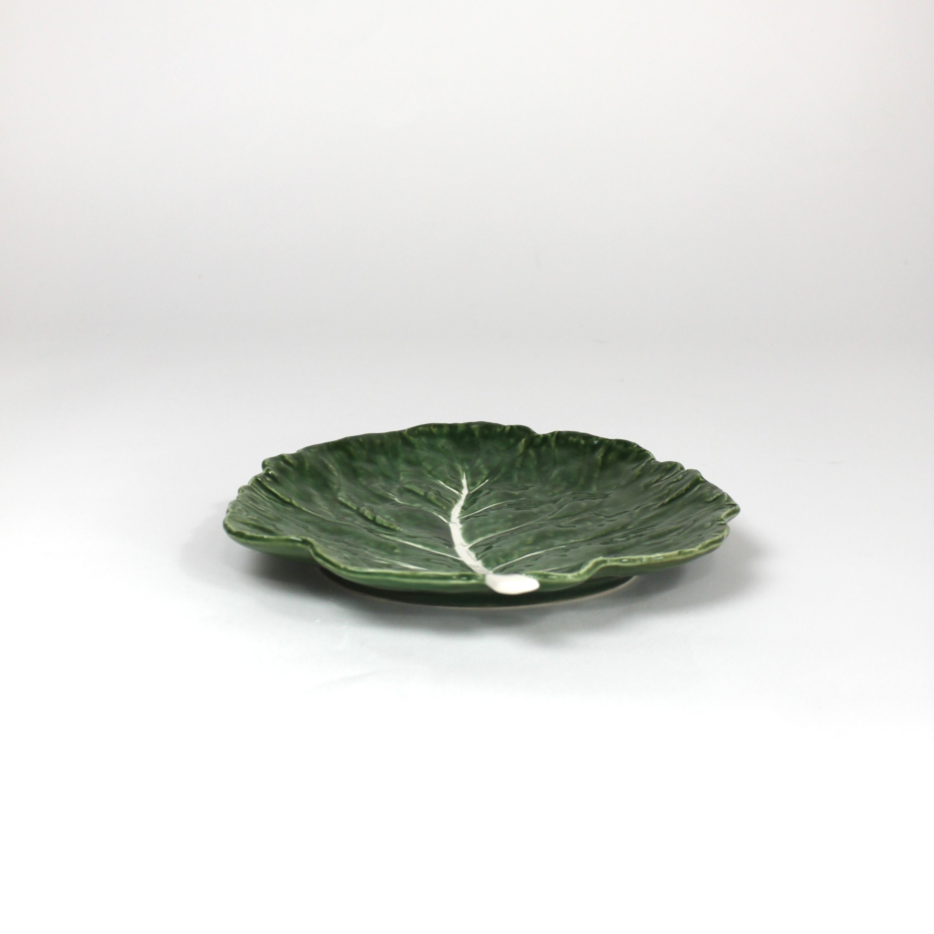 a ceramic green cabbage leaf plate on a white background.