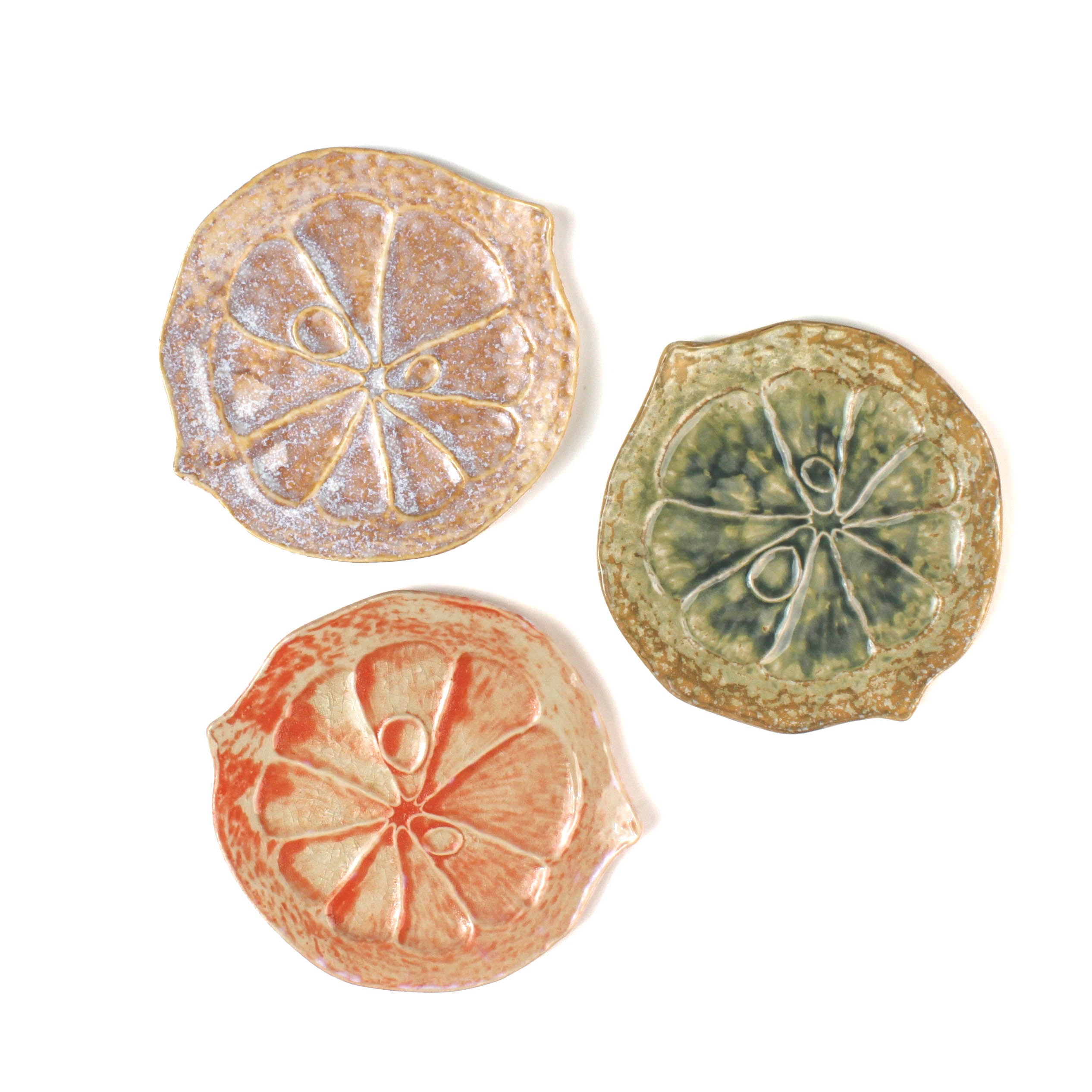 Three citrus fruit shaped ceramic plates with decorative citrus patterns on a white background