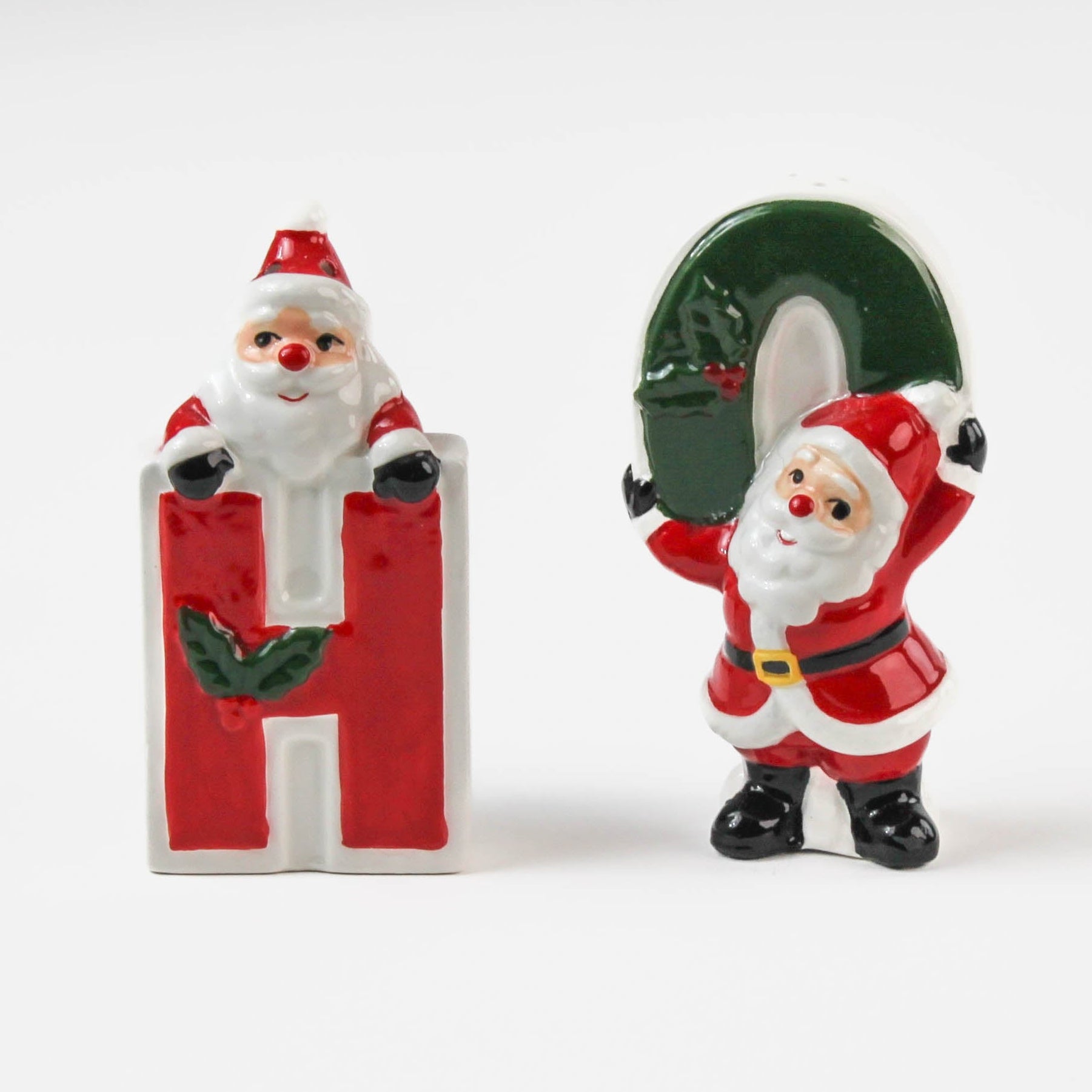 Two ceramic christmas salt and pepper shakers shaped like the letters 'H' and 'O' with Santa Claus figures on a white background.