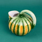 Green and orange ceramic pumpkin-shaped pitcher with a curved handle.