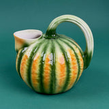 Green and orange ceramic pumpkin-shaped pitcher with a curved handle.