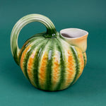 Green and orange ceramic pumpkin-shaped pitcher with a curved handle.