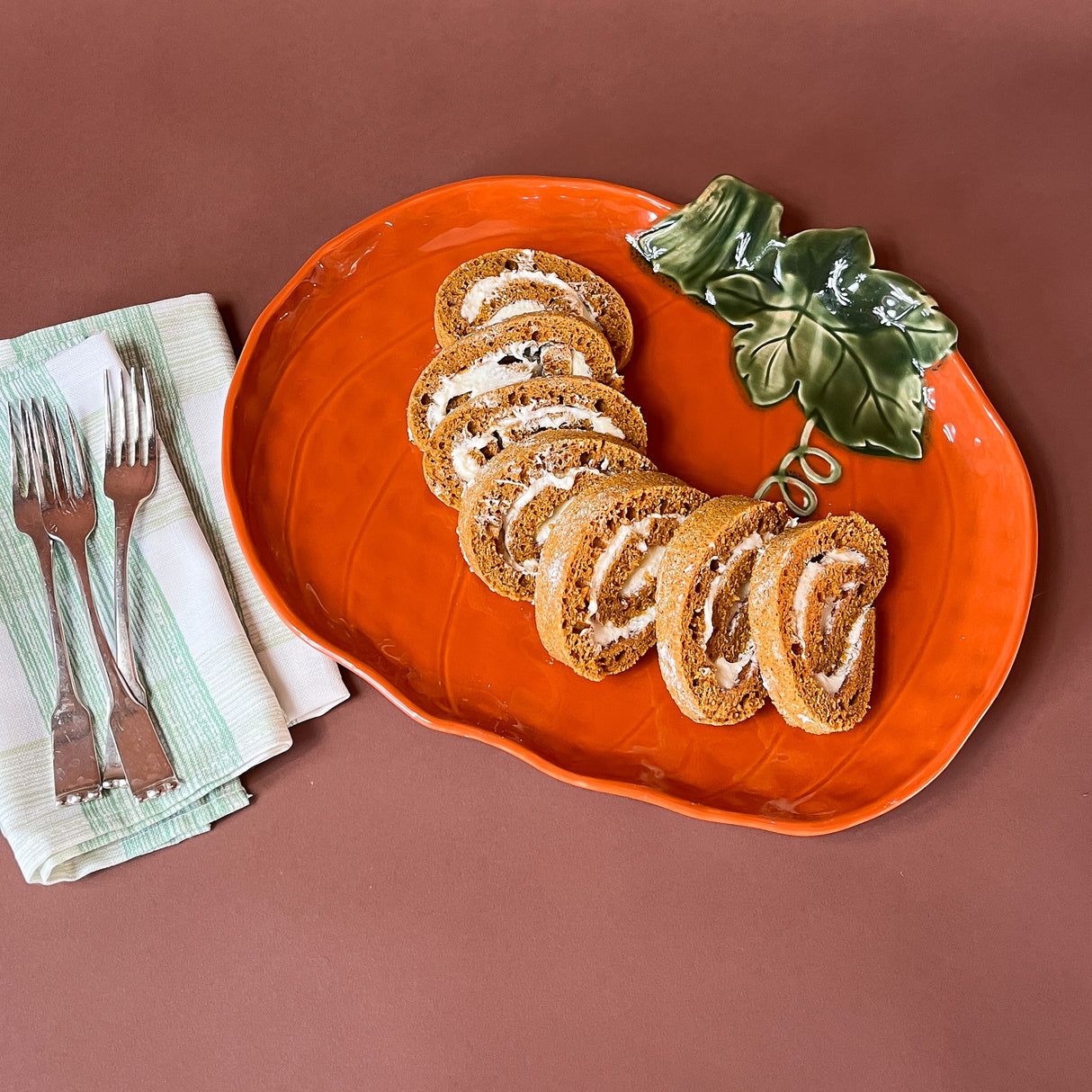 an orange ceramic pumpkin serving platter filled with slices of cream filled cake. 
