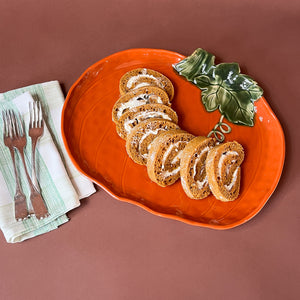 an orange ceramic pumpkin serving platter filled with slices of cream filled cake. 
