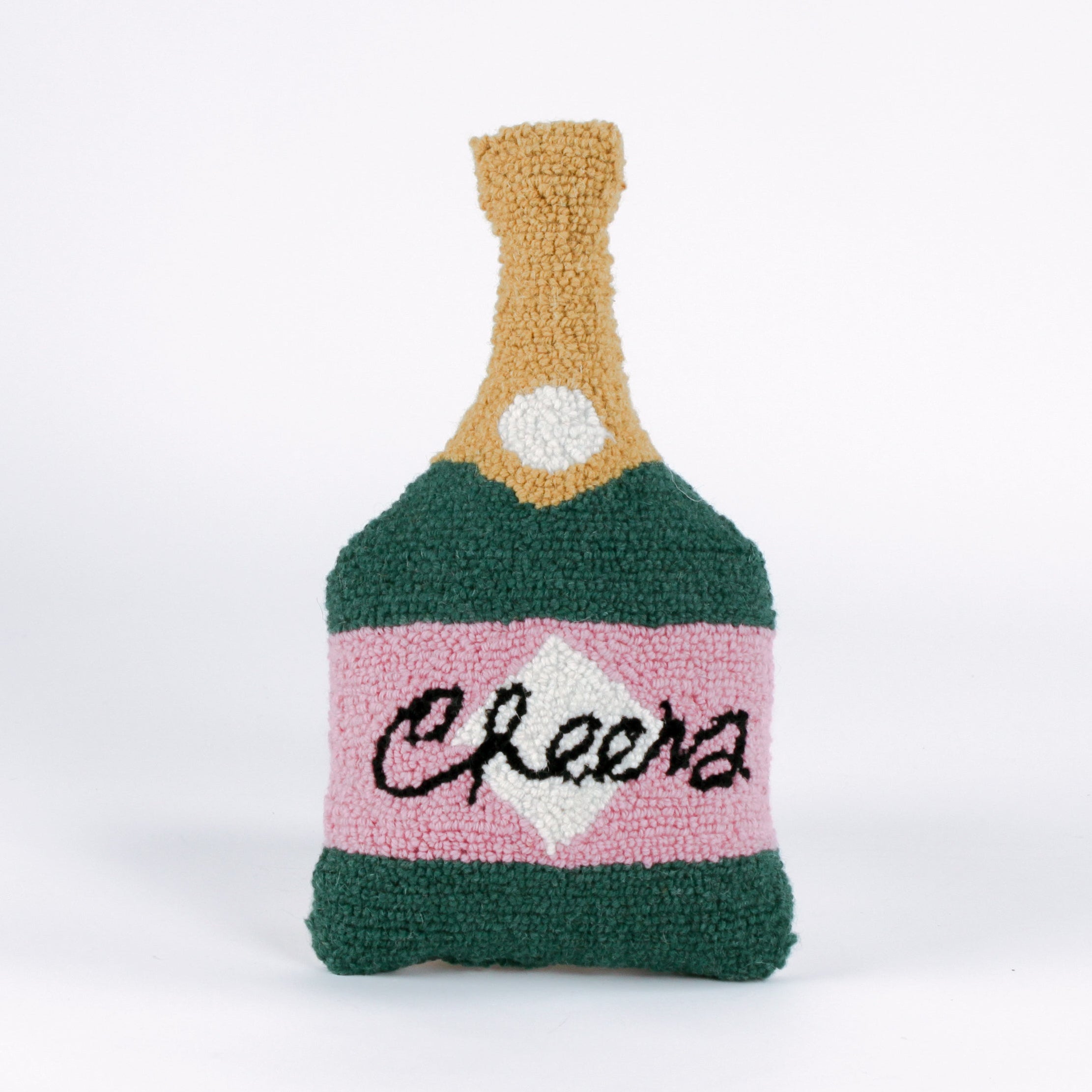 Bottle-shaped decorative pillow with a hooked texture, designed like a champagne bottle in green, pink, and gold colors, featuring the word “Cheers” on the label.