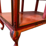 a dark wood chinoiserie side table with two tiers and on rolling casters.