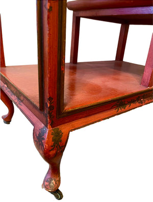 a dark wood chinoiserie side table with two tiers and on rolling casters.