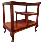 a dark wood chinoiserie side table with two tiers and on rolling casters.