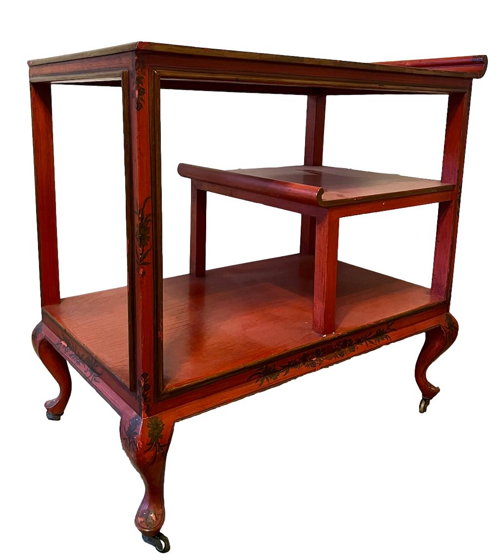 a dark wood chinoiserie side table with two tiers and on rolling casters.