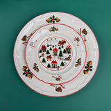 Stacked Christmas village-themed plates with red trim and holiday illustrations on a green background