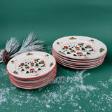 Two stacks of Christmas village-themed plates with red trim and holiday designs on a snowy green background
