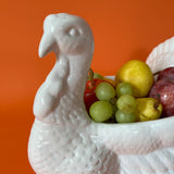 the face of a white ceramic turkey centerpiece filled with fruit