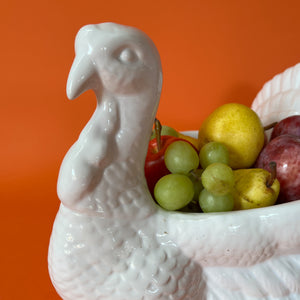 the face of a white ceramic turkey centerpiece filled with fruit