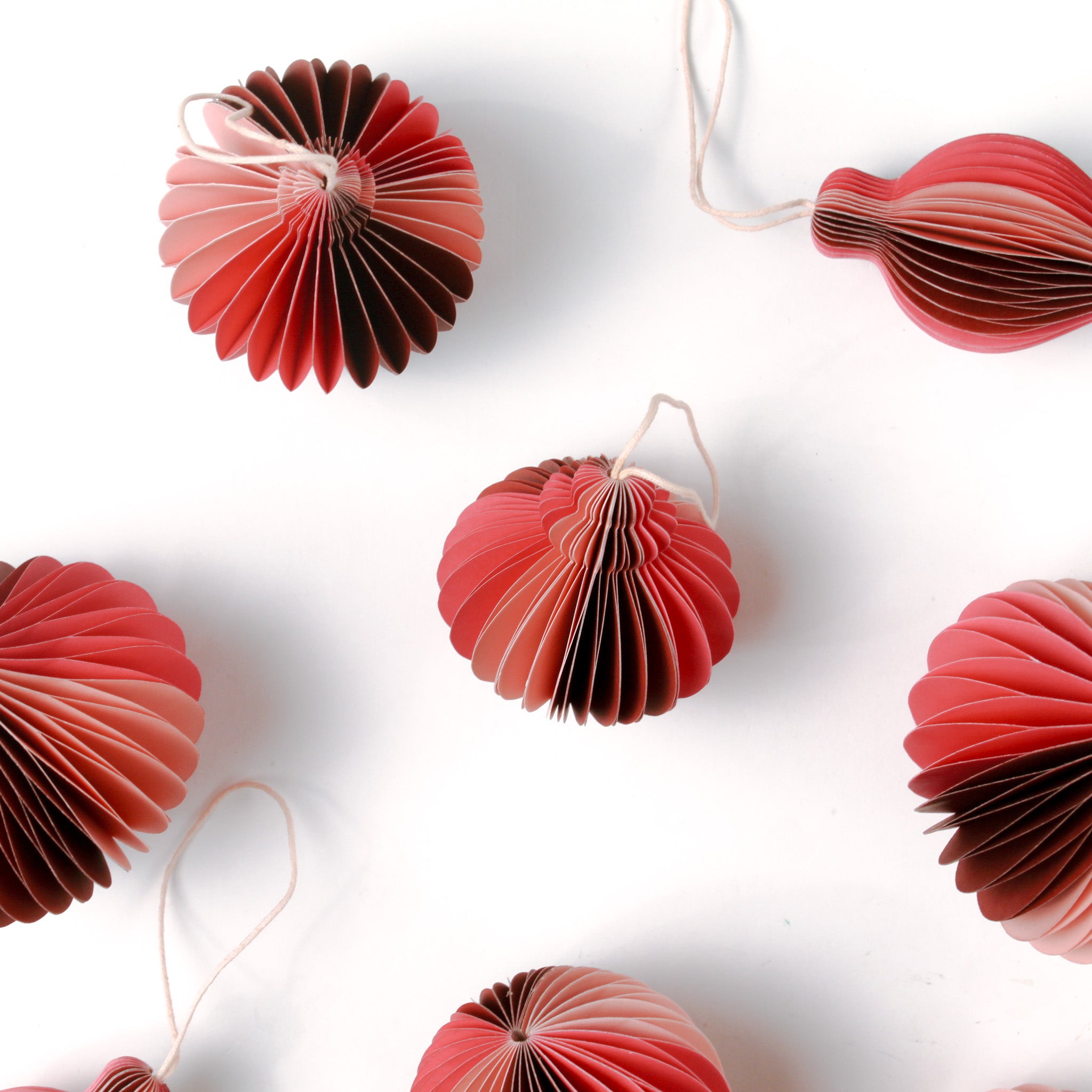 close up of Set of folded paper pink Christmas ornaments in assorted bulb shapes with hanging string