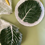 a aerial view of a two green ceramic cabbage leaf plates with napkins next to them from madcap cottage