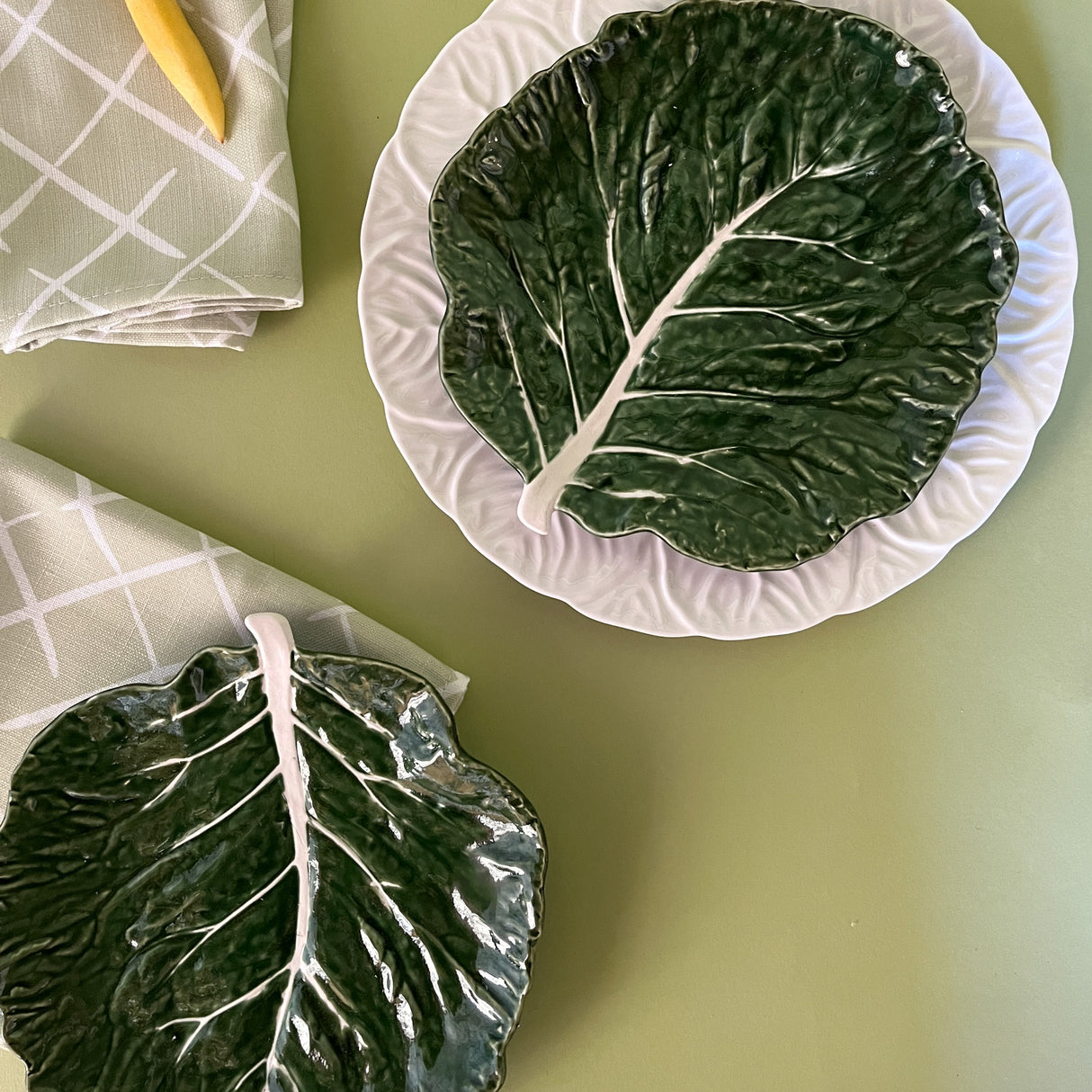 a aerial view of a two green ceramic cabbage leaf plates with napkins next to them from madcap cottage