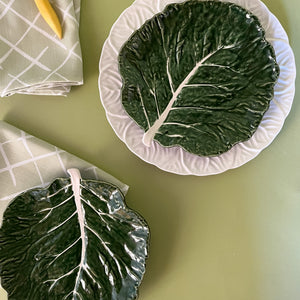 a aerial view of a two green ceramic cabbage leaf plates with napkins next to them from madcap cottage