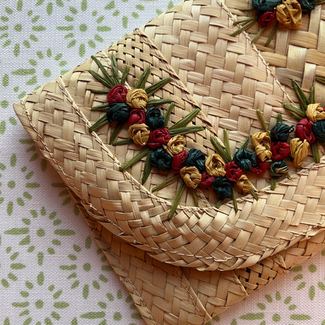 a vintage straw clutch bag with yellow and red flowers around the front