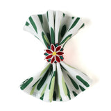 Green brush stroke patterned dinner napkin folded and styled with a red floral napkin ring, arranged for an elegant table setting and coordinated with a Christmas tea towel.