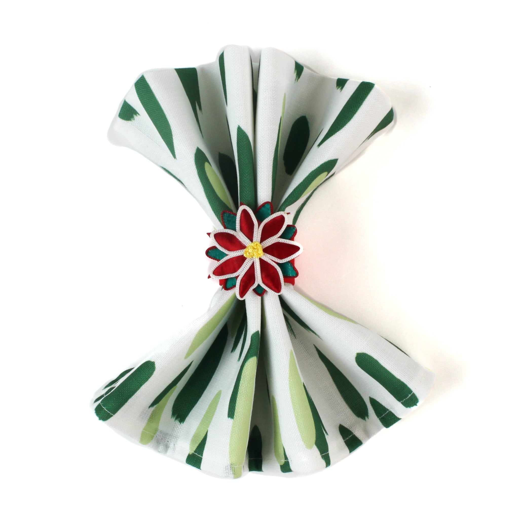 Green brush stroke patterned dinner napkin folded and styled with a red floral napkin ring, arranged for an elegant table setting and coordinated with a Christmas tea towel.