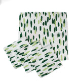 Set of four green brush stroke patterned dinner napkins on a white background, neatly stacked with stitched edges, designed for modern table settings and coordinated with a Christmas tea towel.