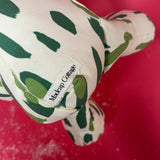 White stuffed elephant toy with green brushstroke pattern and red bow close-up.