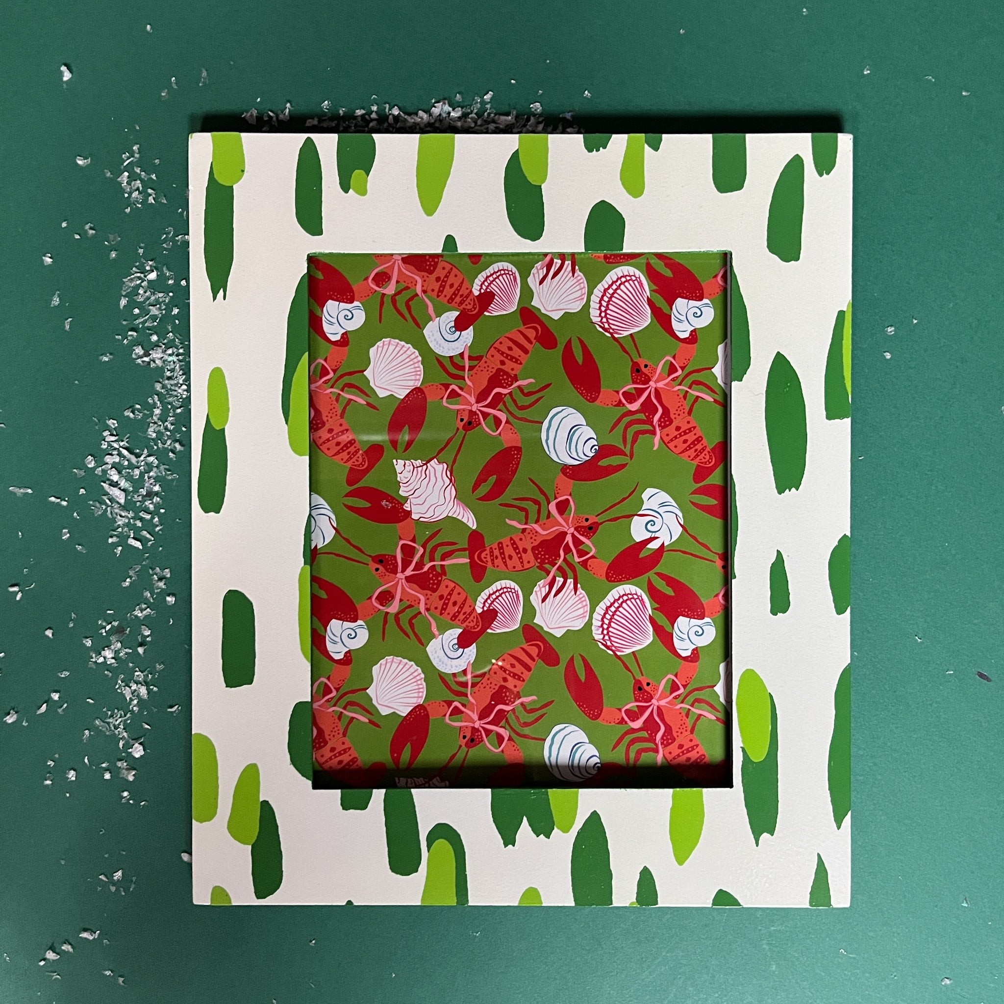 a green and white frame featuring a green brushtroke motif from madcap cottage