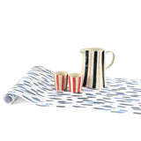 Clubhouse blue paper table runner styled with striped pitcher and matching cups.