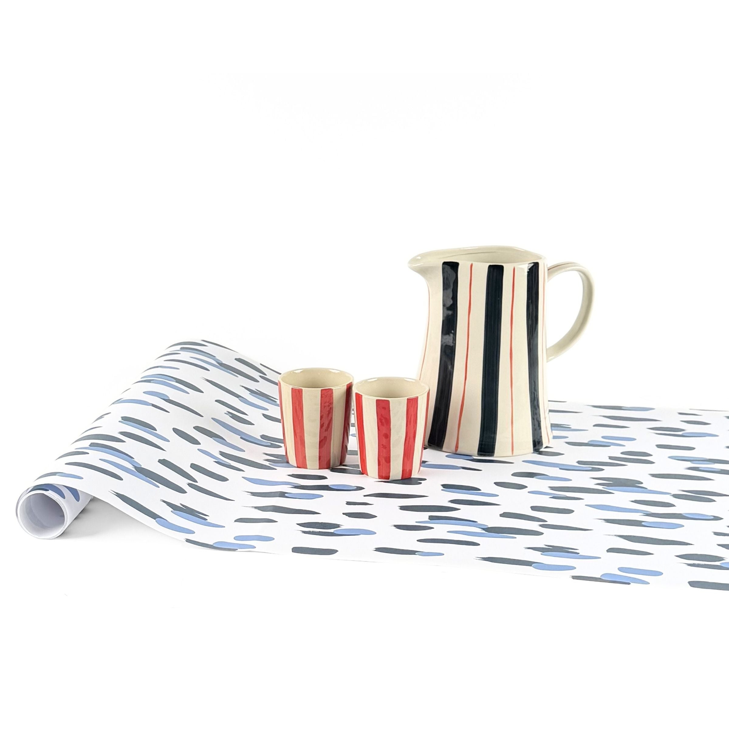 Clubhouse blue paper table runner styled with striped pitcher and matching cups.