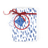 Gift wrapped in blue brushstroke wrapping paper with red ribbon and blue ornament tag.