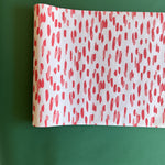 A white and red paper table runner featuring a brushtroke pattern called Club House by Madcap Cottage