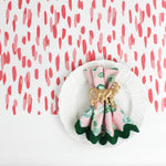 A ceramic plate on a pink and white paper table runner with a brushtroke pattern on a white background