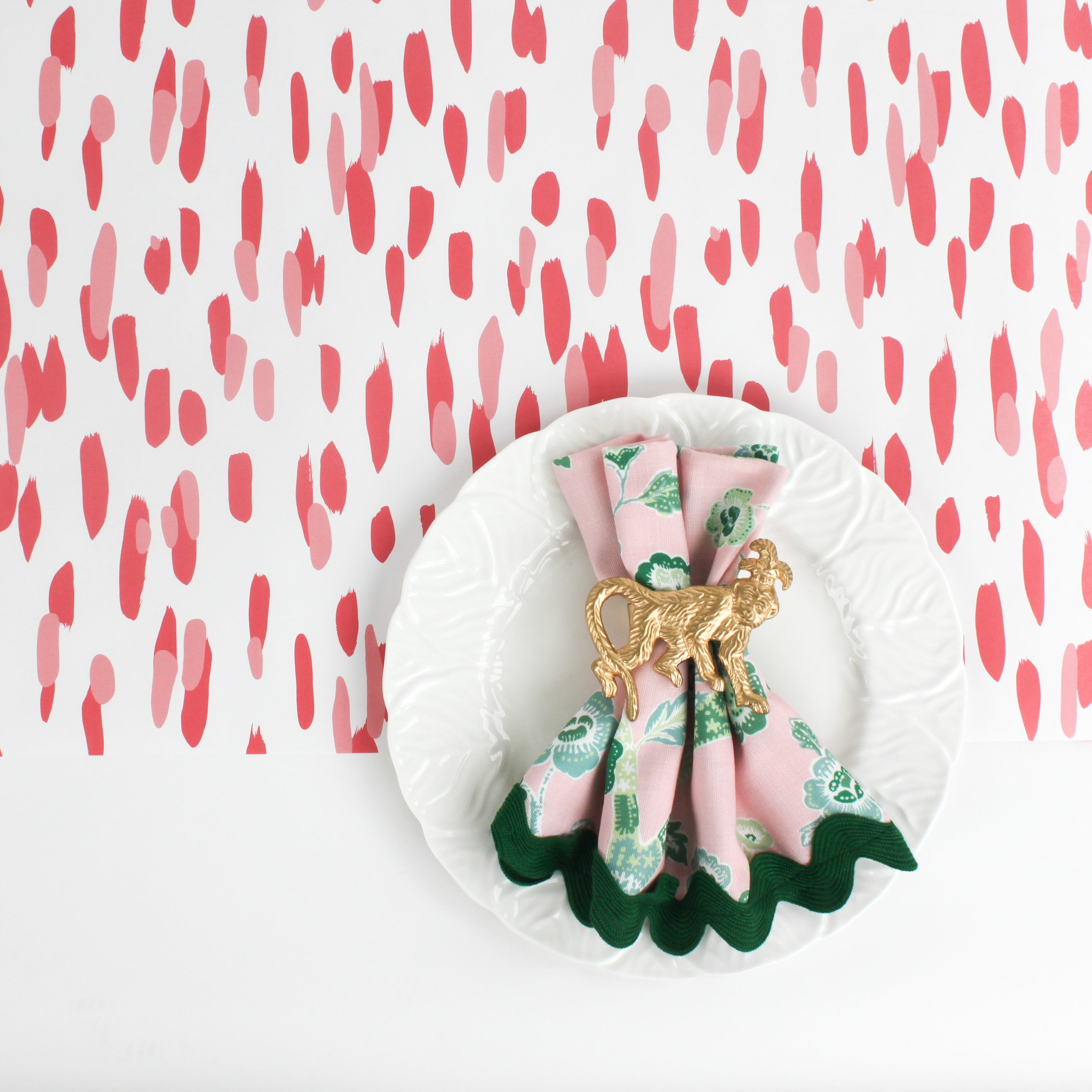 A ceramic plate on a pink and white paper table runner with a brushtroke pattern on a white background