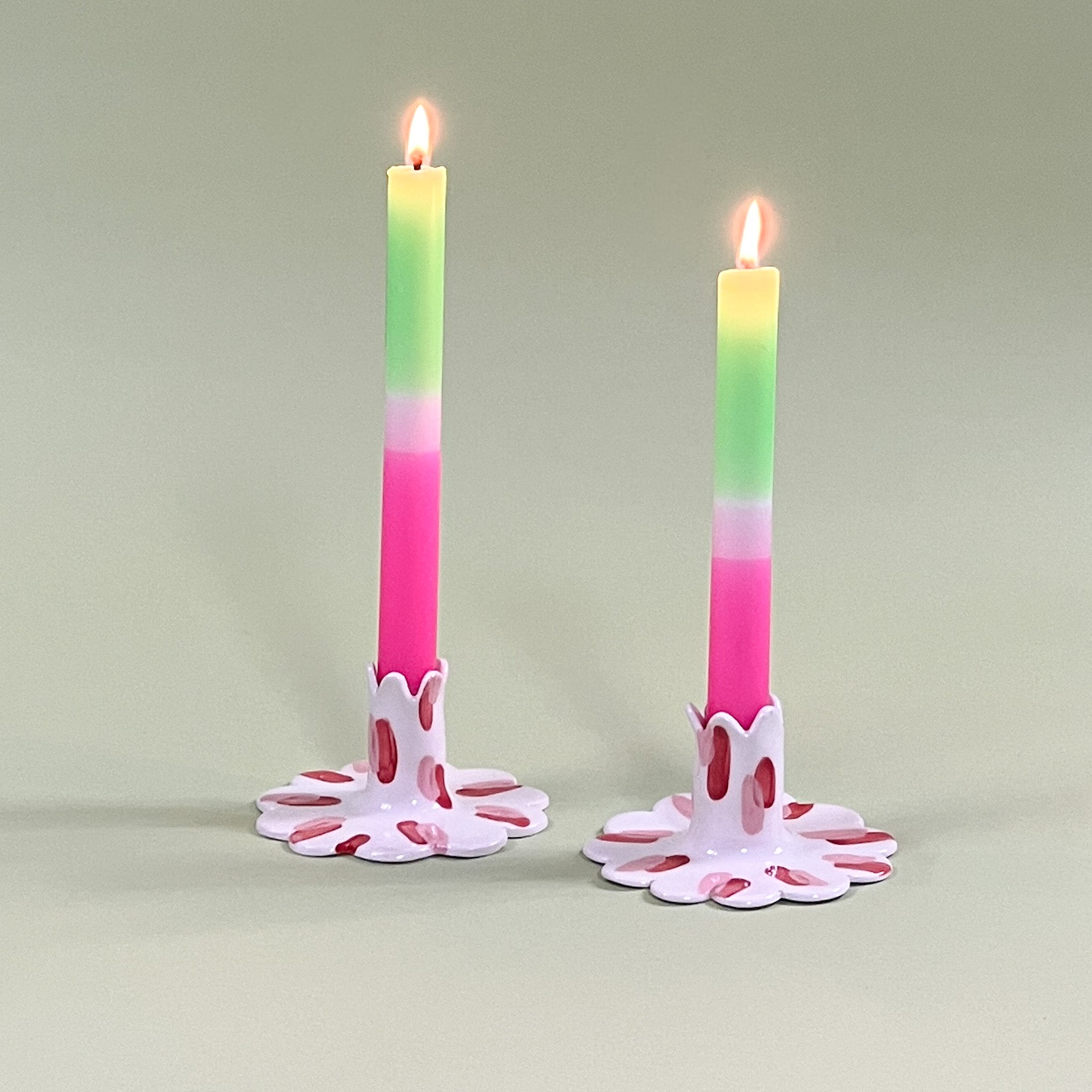 Pair of madcap cottage ceramic candle holders with scalloped edges and a red and Club House pattern holding taper candles.