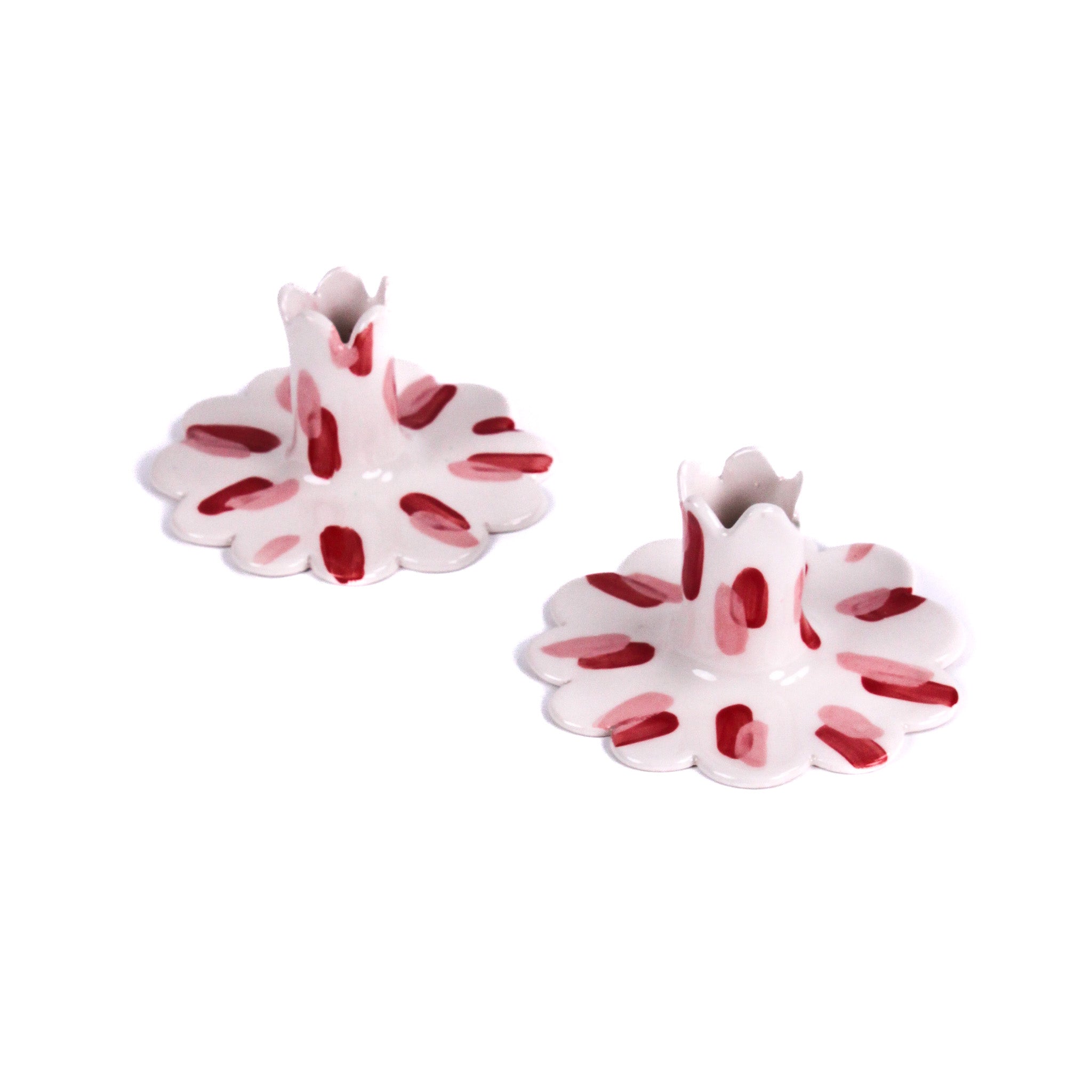 Pair of red and white ceramic petal-shaped candle holders with hand-painted red accents, designed for decorative tabletop display.