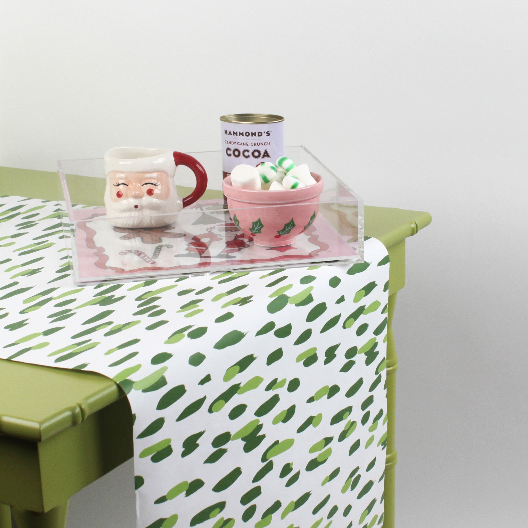 a green table covered with a green and white paper table runner with a brushtroke pattern with some tray and cup on it