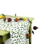 a green table covered with a green and white paper table runner with a brushtroke pattern and a fruit garland on top