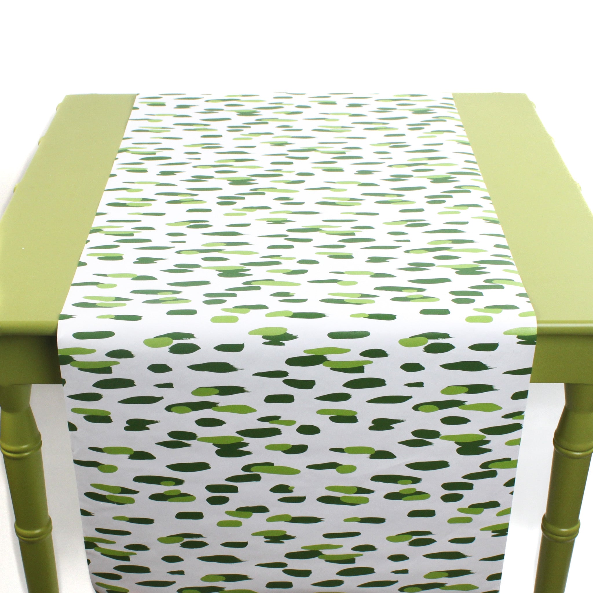 a green table covered with a green and white paper table runner with a brushtroke pattern