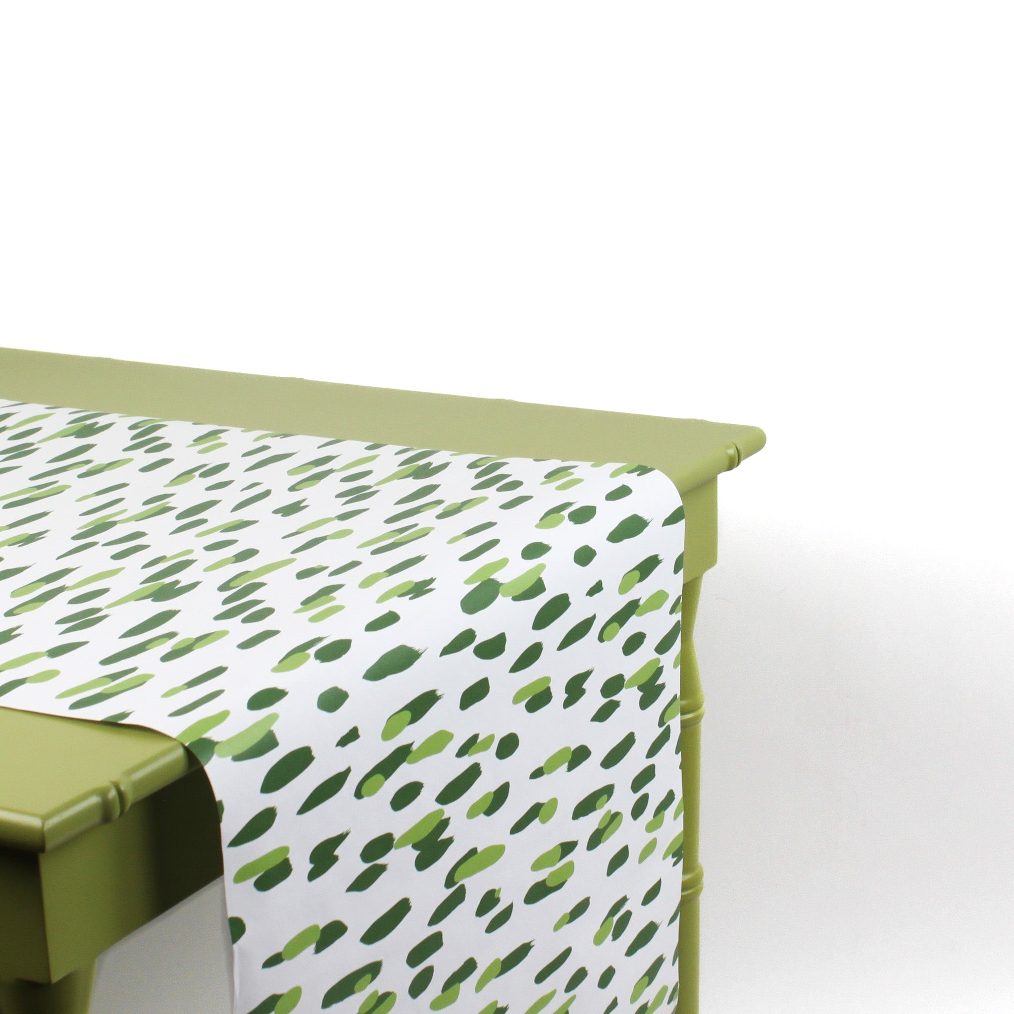 a green table covered with a green and white paper table runner with a brushtroke pattern