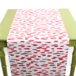 a green table covered with A pink and white paper table runner with a brushtroke pattern on a white background